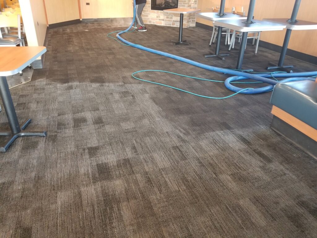 A professional cleaning a patterned commercial carpet in a restaurant by New Dawn's Carpet Cleaning in Cicero, IL.