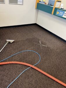 Carpet cleaning equipment on a brown commercial carpet, showing a clean spot, by Reynolds Carpet Care in Henrico, VA.