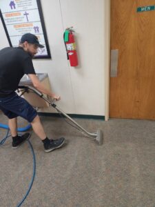 A technician performing commercial carpet cleaning in a hallway for LNC Steam Cleaning in Owasso, OK.