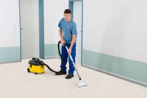 A smiling technician using a commercial carpet cleaning machine on a light-colored carpet for Empire Carpet Cleaning Services in Omaha, NE.