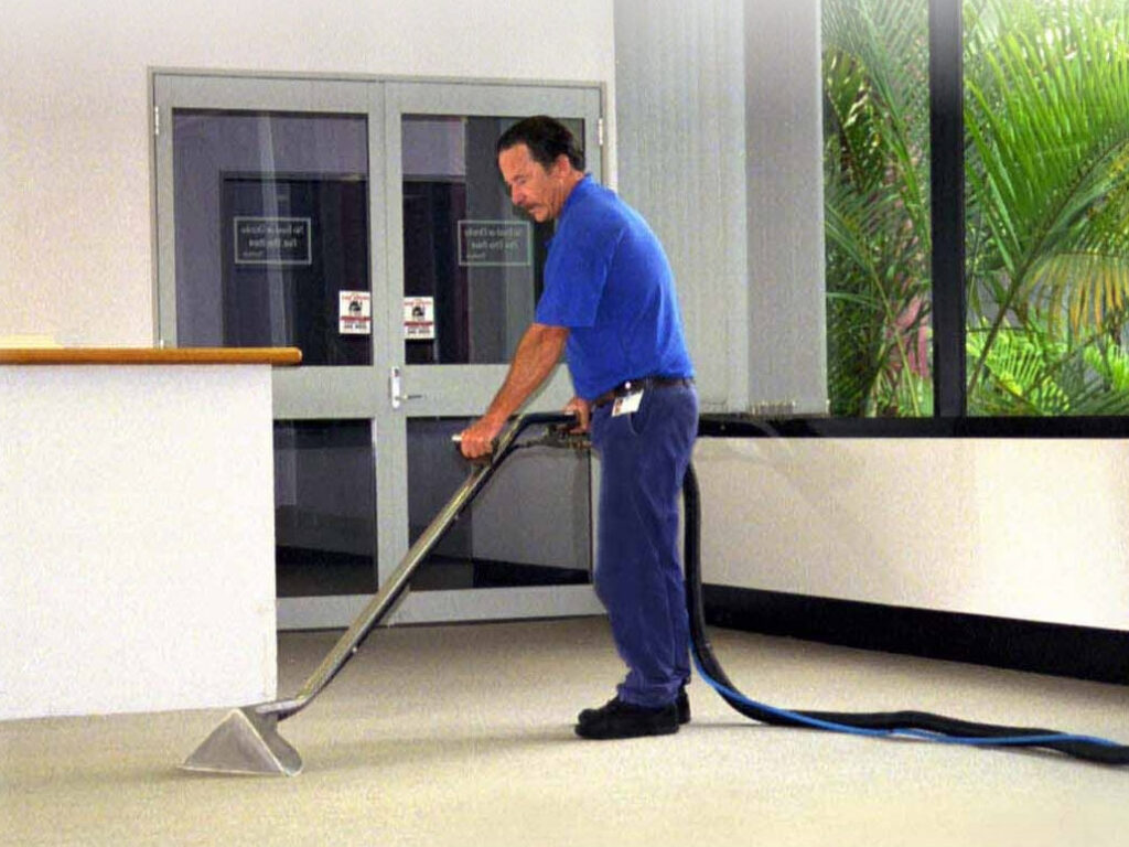 A professional technician from stpaulbestcarpetcleaners.com cleaning commercial carpet with a specialized wand in Saint Paul, MN.