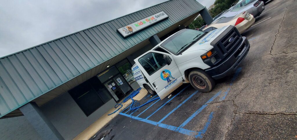 The Spot On Carpet Cleaning of Columbia, SC van with hoses leading into a commercial building for a cleaning service.