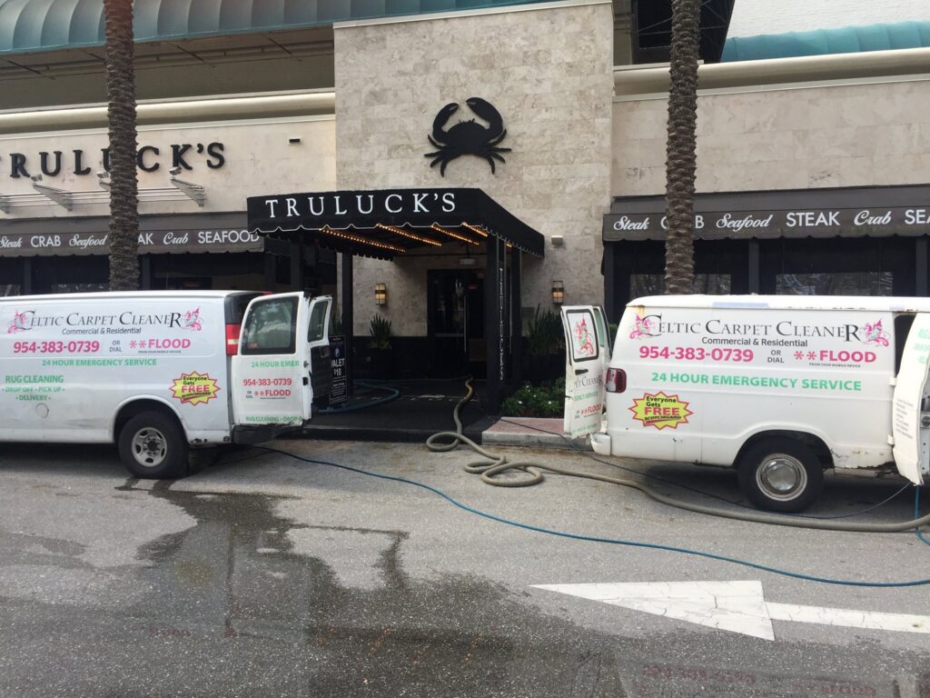 Celtic Carpet Cleaner vans with hoses outside Truluck's, indicating a commercial carpet cleaning job in Fort Lauderdale, FL.