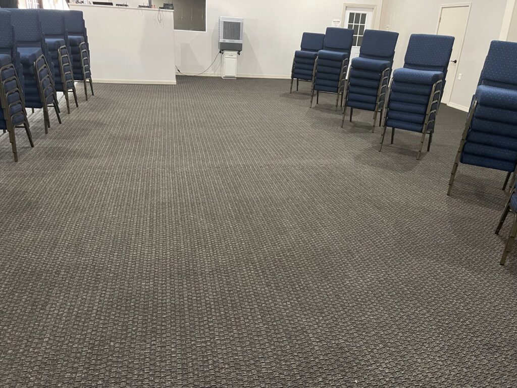 A clean commercial carpet in an event space with stacked chairs, professionally maintained by Carpet PRO Cleaner in Cary, NC.