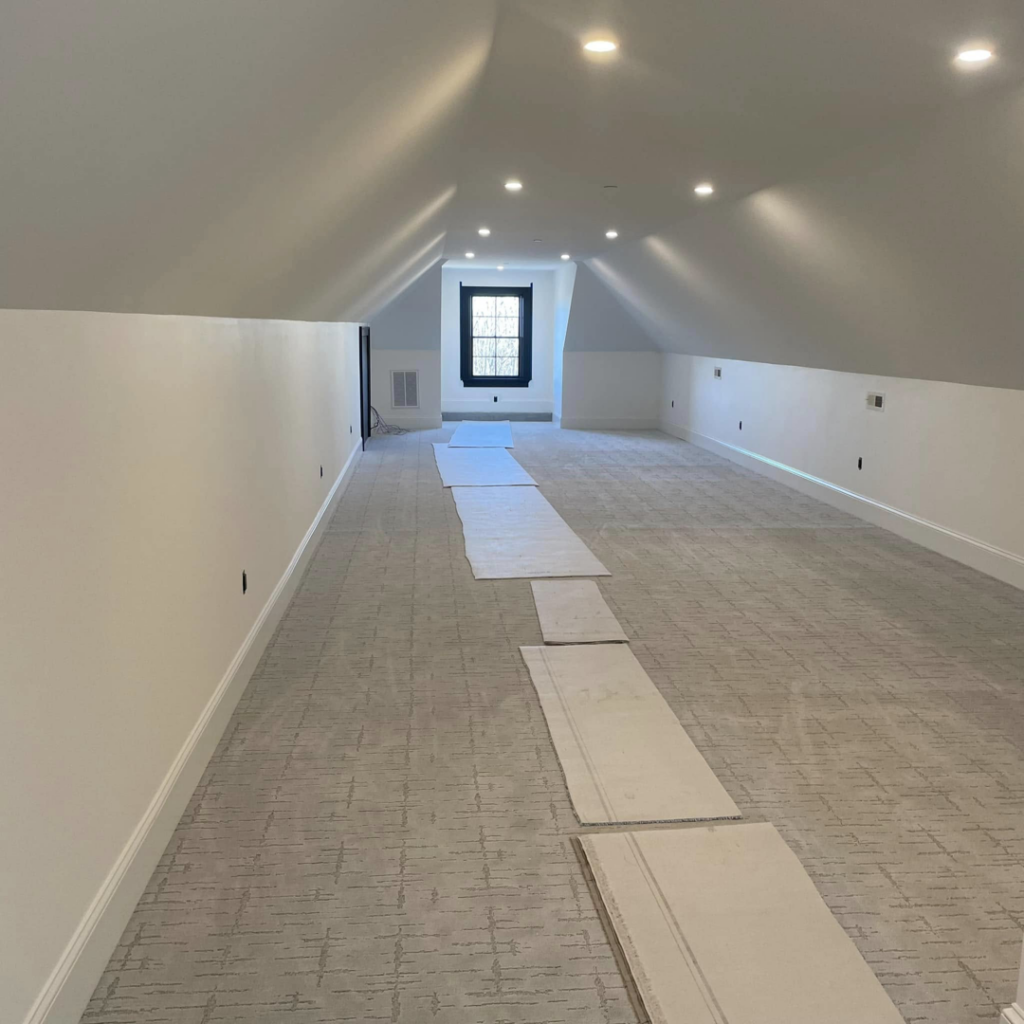 A large room undergoing wall-to-wall carpet installation by J MIKE PONTE FLOOR COVERING in Lowell, MA.