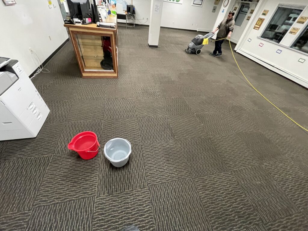 A technician cleaning commercial carpet tiles with a machine by Alaska Floor Care Specialists in Fairbanks, AK.