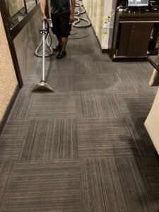 A professional cleaning commercial carpet tiles with a wand at TCK Carpet Cleaning in Indianapolis, IN.