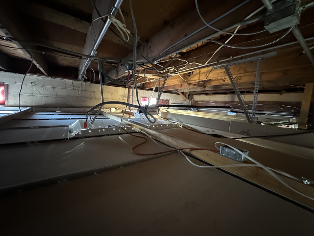 Complex electrical wiring and conduits visible in a commercial ceiling space, installed by Watts Happening Electric in Lakewood, CO.