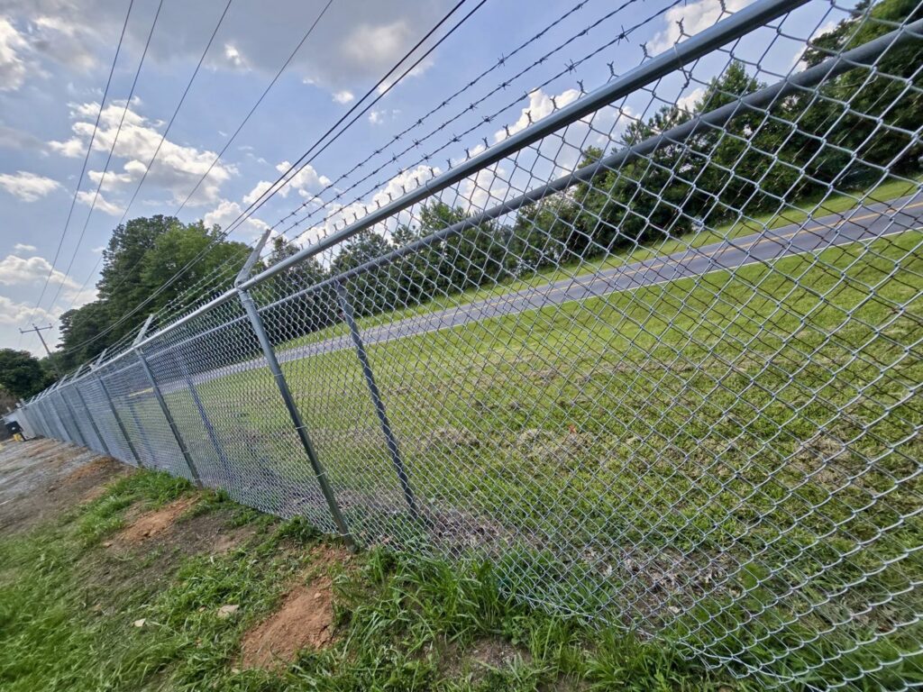 A commercial-grade chain-link fence with barbed wire for enhanced security, installed by Hawk Fences LLC in Johns Creek, GA.
