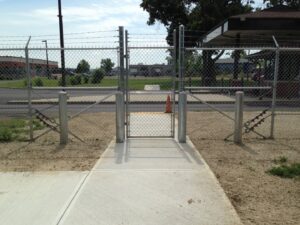 A commercial chain link fence with barbed wire and a gate, installed by Brodeur-Campbell Fence Co. in Springfield, MA, for security.
