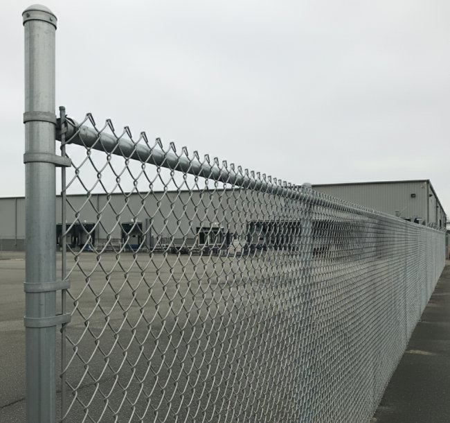 A long chain-link fence providing security for a commercial property by Boost My Home in St. Augustine, FL.