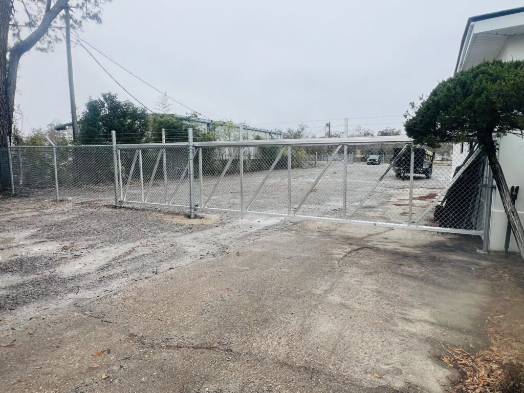 A commercial chain-link fence with a large double gate securing an industrial area, installed by Capitol Fencing in Baton Rouge, LA.