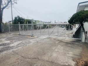 A commercial chain-link fence with a large double gate securing an industrial area, installed by Capitol Fencing in Baton Rouge, LA.