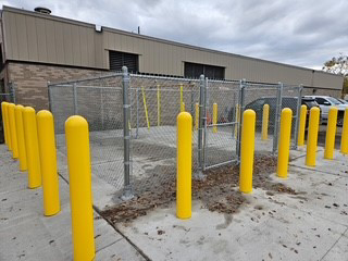 Commercial chain-link fence enclosure with yellow safety bollards installed by Wildfire Products Inc. in West Fargo, ND