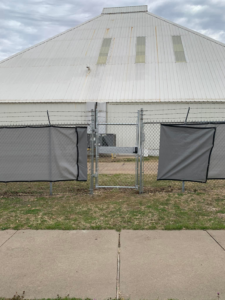 A commercial chain-link fence with a gate, privacy screens, and barbed wire installed by BAR Z Fencing and Welding LLC in Midlothian, TX