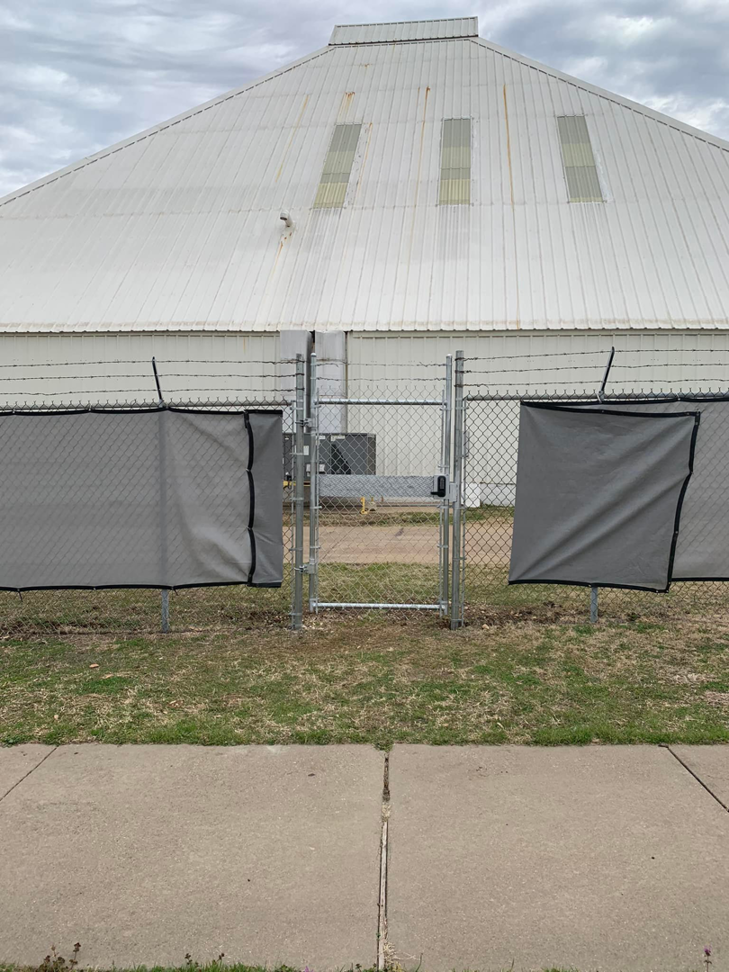 A commercial chain-link fence with a gate, privacy screens, and barbed wire installed by BAR Z Fencing and Welding LLC in Midlothian, TX