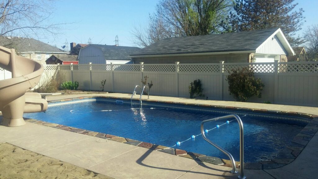 A commercial chain-link fence with privacy slats and barbed wire installed along a paved area by Best Fence & Gate LLC in Louisville, KY.