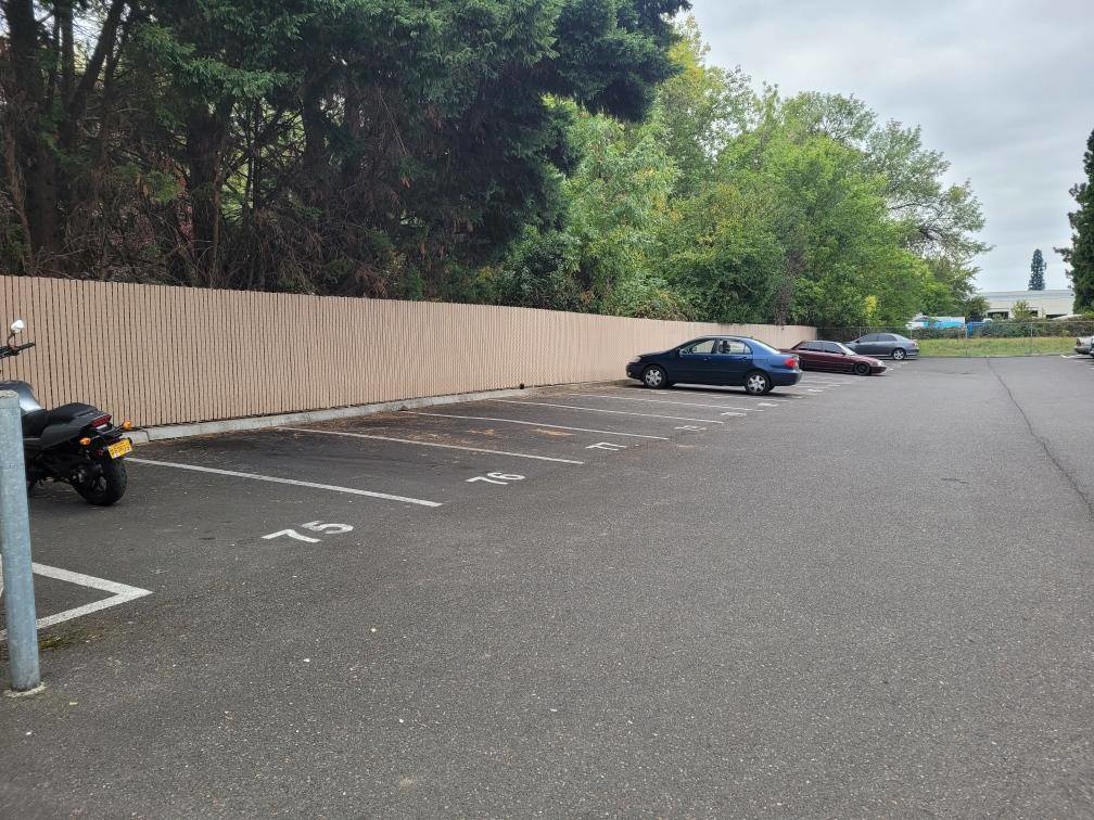 A commercial chain-link fence with privacy slats installed along a parking lot by Howell Fence Inc. in Oregon City, OR.