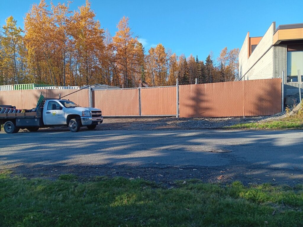 A commercial chain-link fence with privacy slats installed, with a work truck nearby, by Five Star Fence Co. in Anchorage, AK.