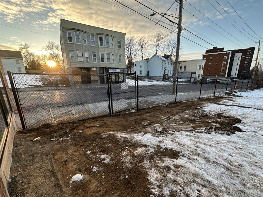 A newly installed black chain-link fence with a gate along a street by Vision One Construction in Schenectady, NY
