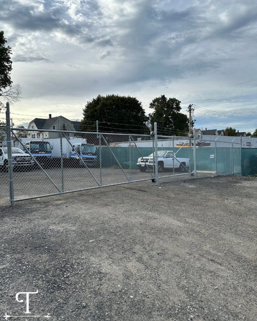 A commercial chain-link fence with barbed wire, enclosing a business yard, installed by Teto's Fence Installation in Bridgeport, CT.