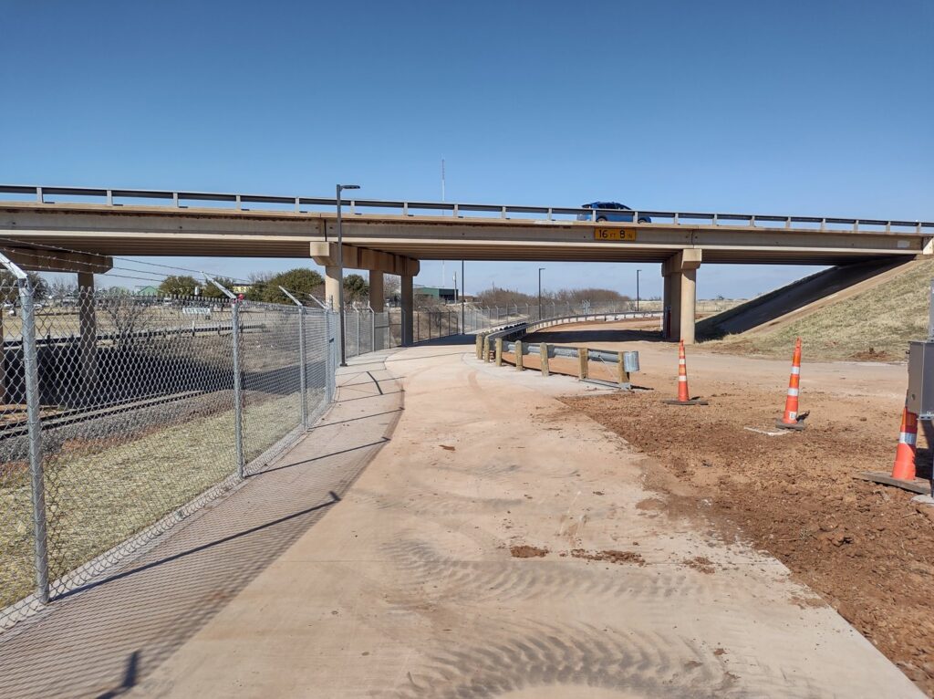 A commercial chain-link fence installed under a highway overpass by Pro Insulation and Fence in Wichita Falls, TX.