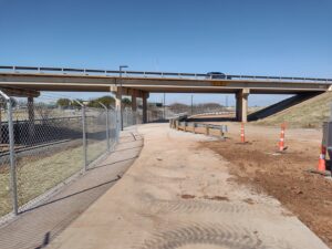 A commercial chain-link fence installed under a highway overpass by Pro Insulation and Fence in Wichita Falls, TX.