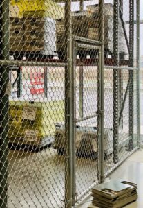 A commercial chain link fence with a gate inside a warehouse installed by 2 Guys & A Girl Lawn Care in Thornton, CO.