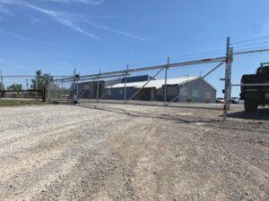 A commercial chain-link fence with barbed wire and an automatic gate by ProScape Outdoor Construction LLC in Norman, OK.