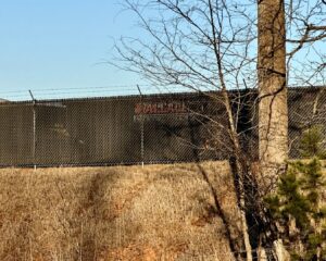A robust commercial chain-link fence with privacy slats and barbed wire, installed by Cavitt Fencing in Concord, NC.