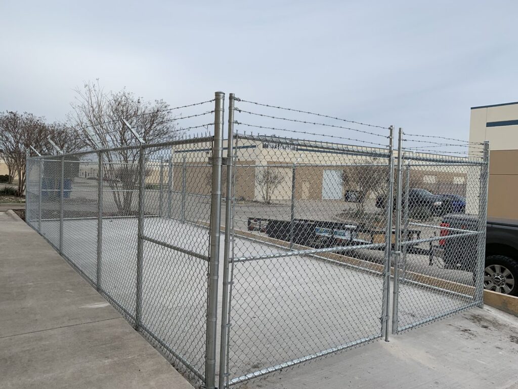 A commercial chain-link security enclosure with barbed wire, expertly constructed by G L Fence & Remodeling in Arlington, TX.