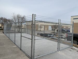A commercial chain-link security enclosure with barbed wire, expertly constructed by G L Fence & Remodeling in Arlington, TX.