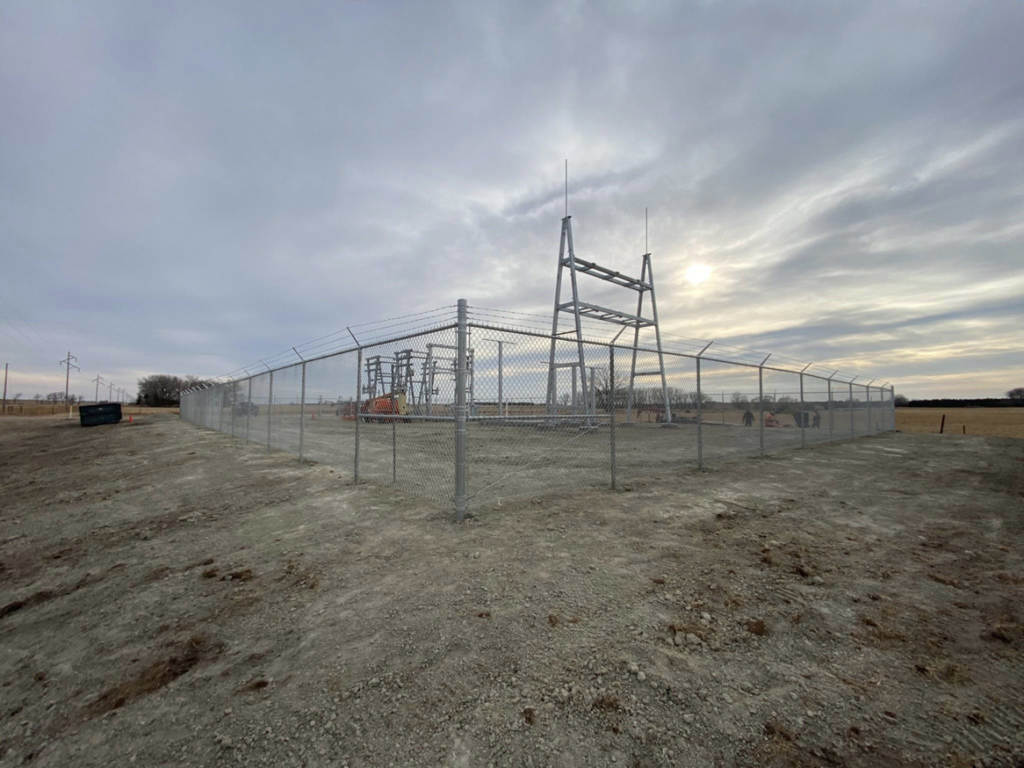 A commercial chain-link security fence with barbed wire installed around a site by Big Red Fencing LLC in Waverly, NE.