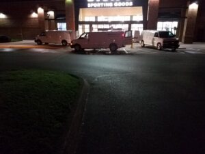 Multiple commercial cleaning vans parked outside a large building at night, for Mid State Contract Cleaners in Nashville, TN.