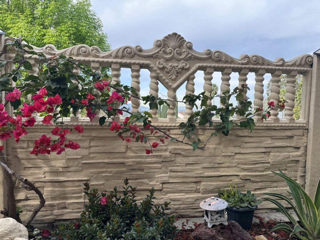 A long commercial concrete fence with a stacked stone texture and barbed wire by StackWall Manufacturing in Pomona, CA.