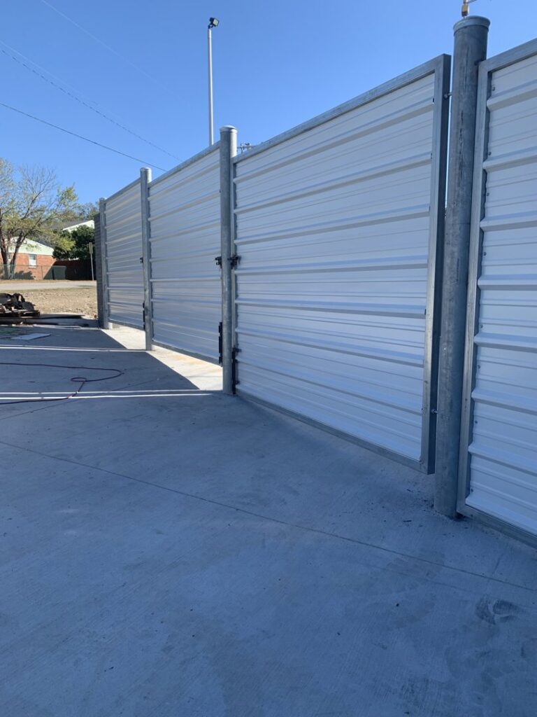 A commercial-style fence constructed with corrugated metal panels by Craftsman Automatic Gates in Dallas, TX.