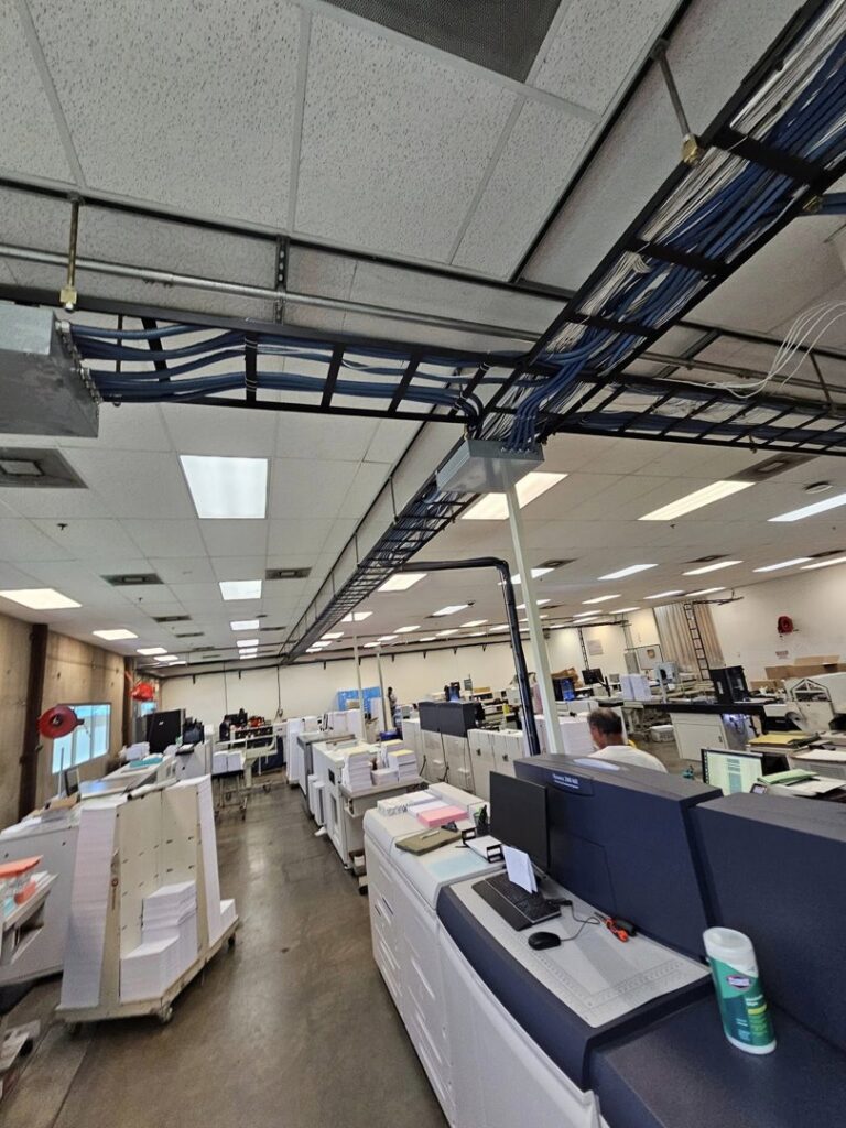 Overhead cable trays with blue data cabling installed in a commercial space by Bee Thumb Electric in North Highlands, CA.