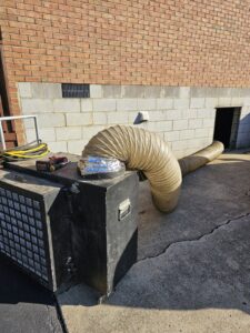 A commercial duct cleaning or sealing setup with large flexible ducting outside a building by Aces of Air Inc. in Georgetown, KY.