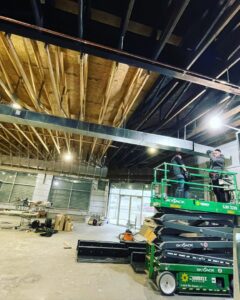 HVAC technicians installing large commercial ductwork using a scissor lift at a job site for JL Heating & AC LLC in Chicago, IL