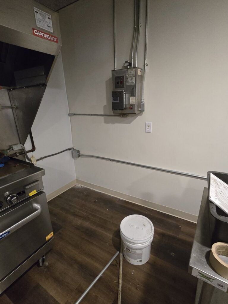 Electrical conduits and a control panel installed on a wall in a commercial kitchen by DHJ Electric in Methuen, MA.