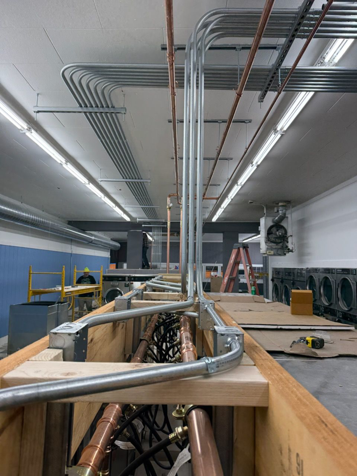 Extensive electrical conduit and copper piping installation in a commercial laundry facility by Pro Circuit Electric in Peoria, IL.