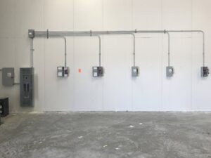 New electrical conduits and panels installed on a white wall in a commercial building, showcasing work by AK Electrical, LLC in Mesquite, TX.