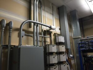 Commercial electrical conduit and panel installation on a wall, with network racks in the background, by Moser Electric in Wisconsin Rapids, WI.