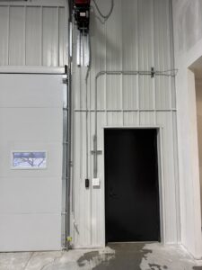 Commercial electrical conduit and wiring installation next to a garage door by TF Electrical Solutions in Omaha, NE.