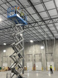 Electricians on a scissor lift installing electrical conduit in a commercial building for Cardinal Electric in Sayreville, NJ