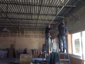 Electricians installing electrical components and wiring in a commercial ceiling at Allied Electric Company of Minnesota in Minneapolis, MN