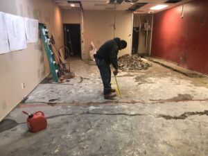 A worker measuring for electrical conduit layout on a commercial floor by Detroit Voltage in Detroit, MI.