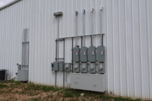 Commercial electrical meter and conduit installation on a building exterior by All American Pro Electric LLC in Cedar Creek, TX.