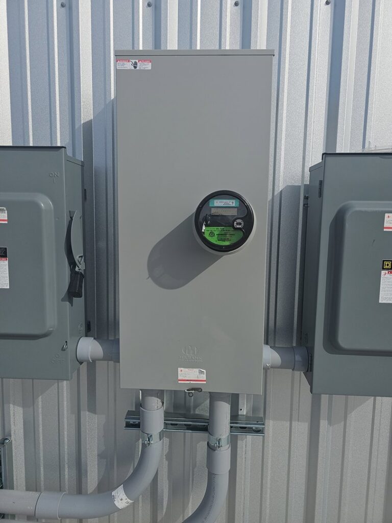 A commercial electrical meter and service panel installed on a corrugated wall by Tesla Alarm and Electrical in Plano, TX