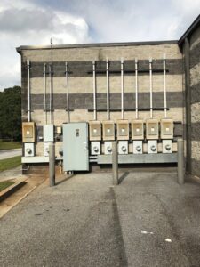 Exterior view of a commercial building showing multiple electrical meters and conduits by McCall Enterprises in Atlanta, GA.